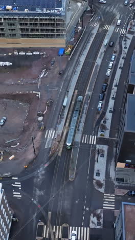 vertical drone shot following a lightrail on the streets of helsinki, winter day