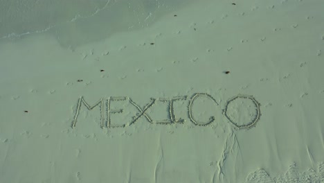 méxico inscrito en la arena de una playa y se hace más grande