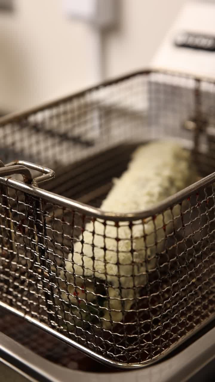 Chef's Hand in Glove Placing Breaded Food into Deep Fryer Basket