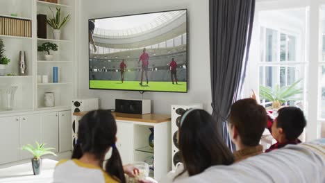 Composite-of-happy-family-sitting-at-home-together-watching-rugby-match-on-tv