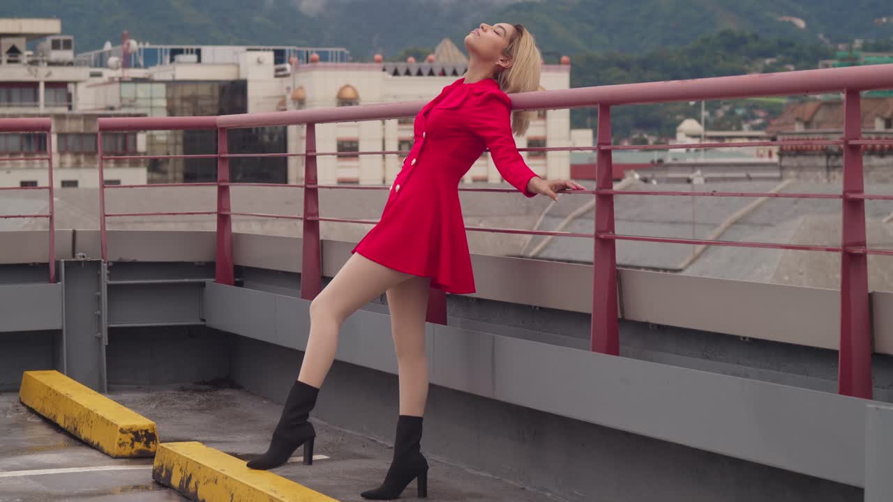 Su un tetto a Port of Spain, Trinidad, una giovane ragazza ispanica indossa un vestito rosso, con alti edifici che completano la scena