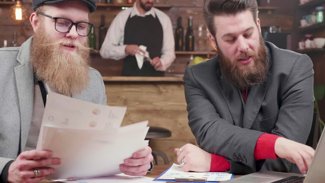 Businessmen Discussing Graphs at a Bar