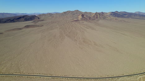 aerial flying over arid desert landscape with road running through