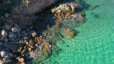 Toma-Aérea-De-Rocas-En-Agua-Verde-Esmeralda-Junto-Al-Acantilado-En-El-Sur-De-Cerdeña,-Italia