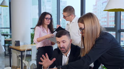 boss leader and female subordinate discussing work at the foreground. couple of colleagues having a talk looking at papers at the backdrop.