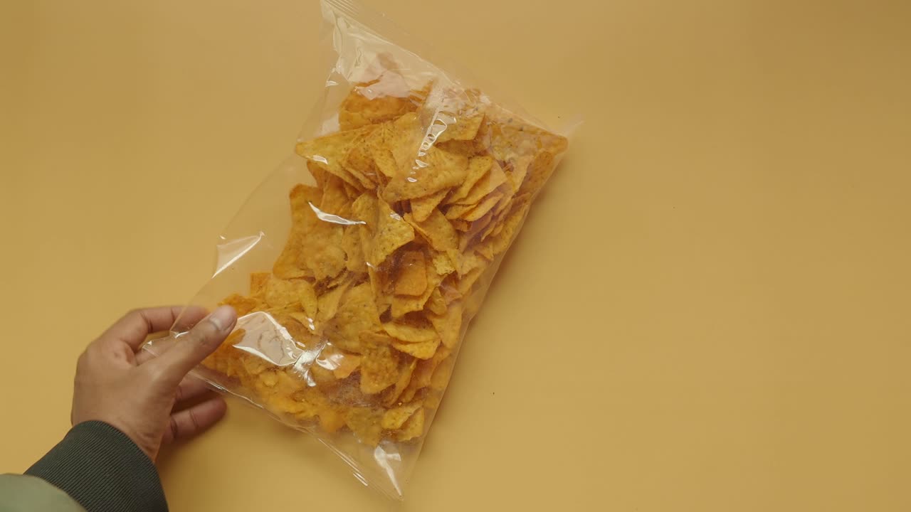 primer plano de la mano sosteniendo una bolsa de papas fritas