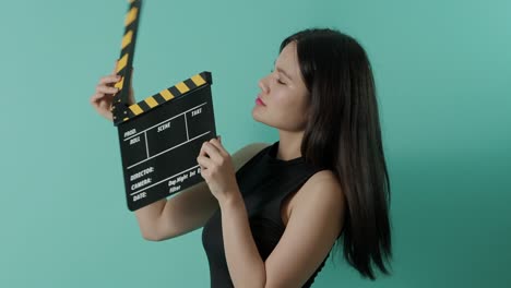 movie slate and little sexy cute asian girl. woman holding and clapping movie clapperboard or film slate with green screen background. camera zooming in and out to show her smile. video production.