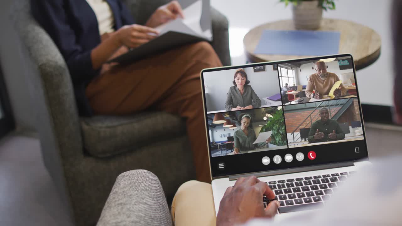 African american man using laptop for video call, with diverse business colleagues on screen