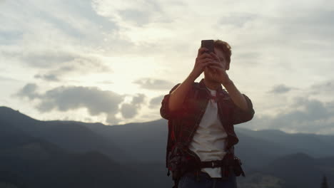 Happy-tourist-take-photo-using-phone-camera-on-picturesque-mountains-landscape.