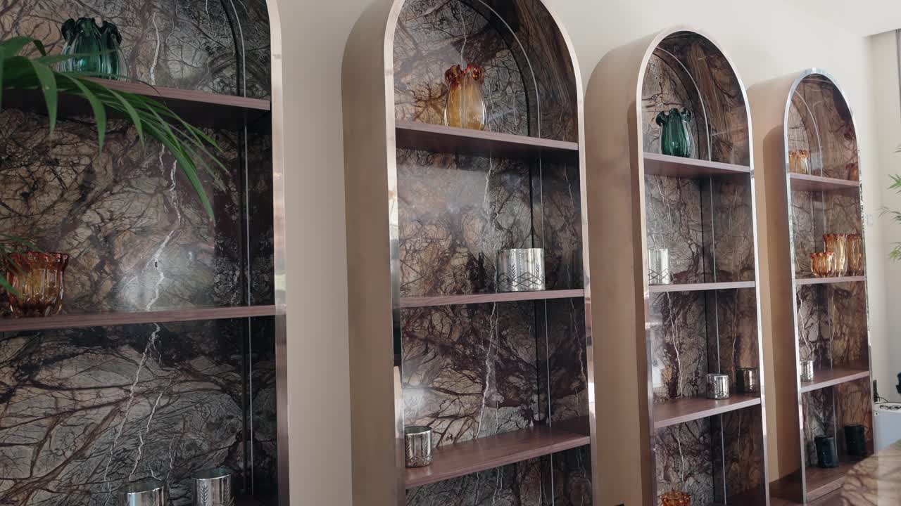 Modern glass vases on arched marble wall shelves with soft natural lighting