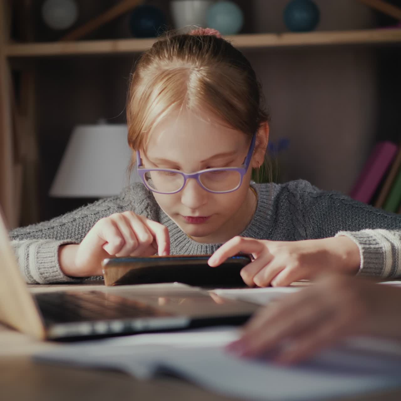 un niño juega en un teléfono inteligente cerca de un padre que trabaja en casa en cuarentena