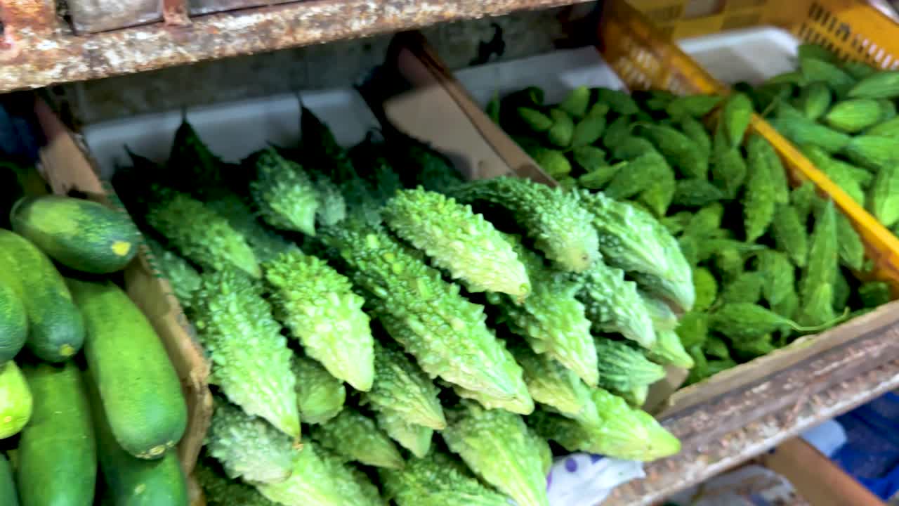 Close-up of bitter melon and cucumber baskets in bright, natural light at local vegetable market