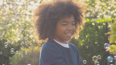 Niño-Sonriente-Al-Aire-Libre-Divirtiéndose-Jugando-Con-Burbujas-En-El-Jardín