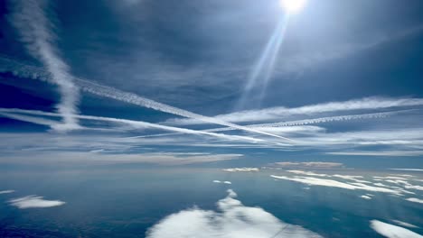 Cielo-Ajetreado-Con-Las-Estelas-De-Cruce-De-Jets-Volando-A-Altos-Niveles,-Con-Un-Cielo-Azul-Profundo-Y-Bengalas-Y-Rayos-De-Sol