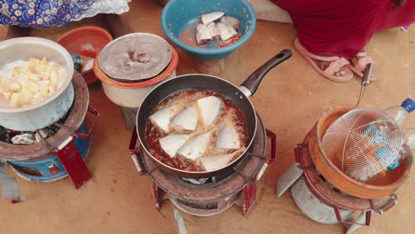 outdoor cooking scene with fish frying in oil