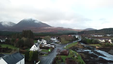 Aerial-pedestal-of-a-little-village-in-the-foreground-and-snowy-mountain-tops-in-the-background