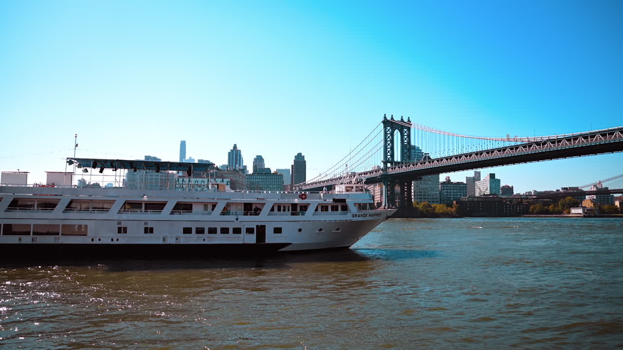 New York, USA, 9 August 2025: Large cruise ship sailing under Manhattan Bridge in New York. A white passenger ship passes under the Manhattan Bridge with downtown New York in the background