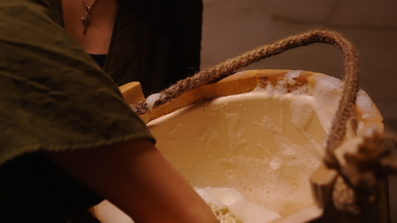 Woman washing in a wooden bucket