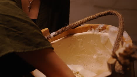woman washing in a wooden bucket