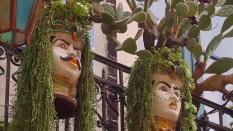 static shot of a pair of sicilian moorish heads with plants and cactus hanging from them, in taormina, sicily, italy (sicilia, italia)