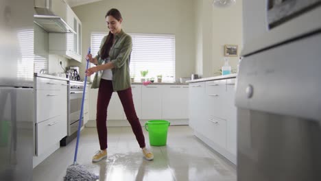 Mujer-Caucásica-Feliz-Limpiando-El-Suelo-Con-Fregona-Y-Cubo-De-Agua-En-Casa