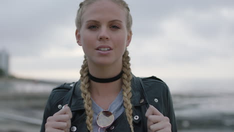 portrait of confident blonde woman wearing leather jacket smiling confident in seaside background