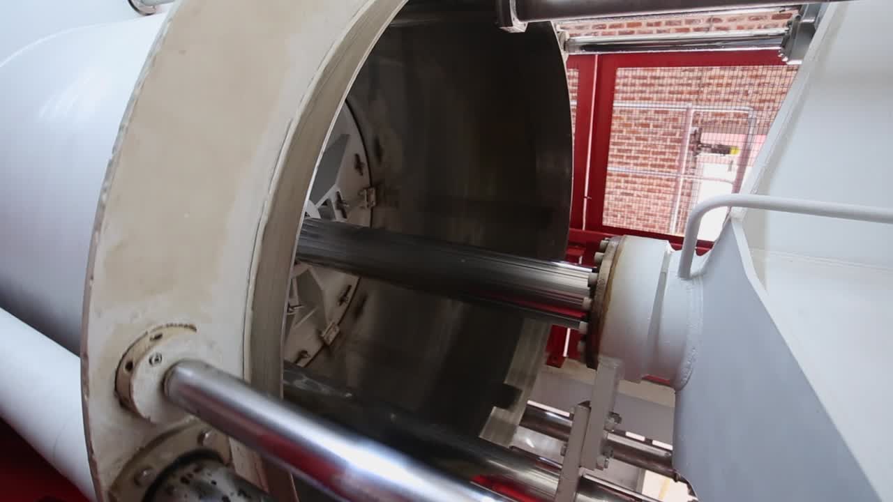 Large heavy rotating orchard fruit press crushes apples into cider pulp