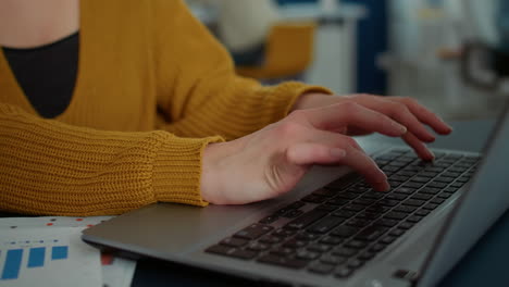 Closeup-on-woman-hands-typing-on-laptop-keyboard-and-smiling-at-camera-sitting-at-desk