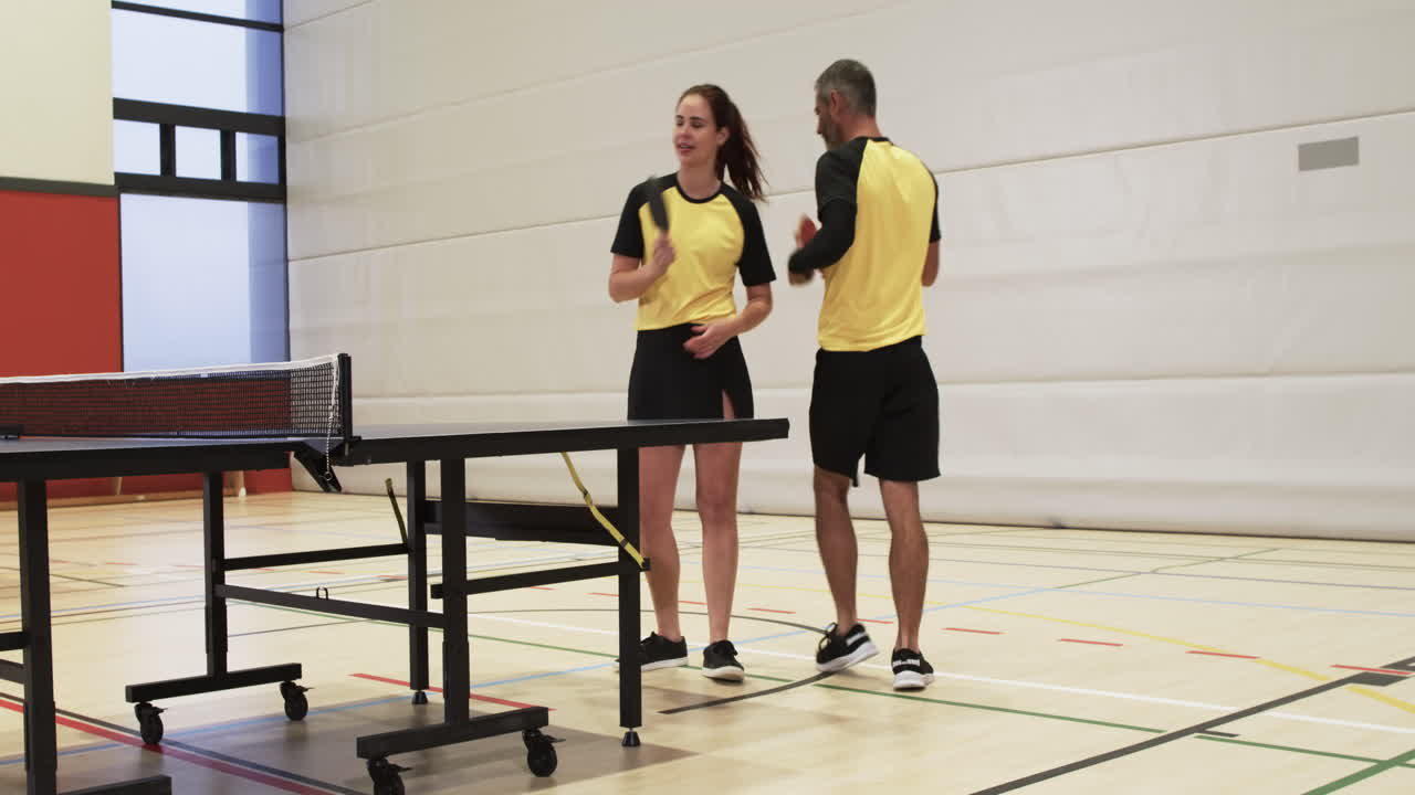 Playing table tennis, man and woman in sportswear competing in gym