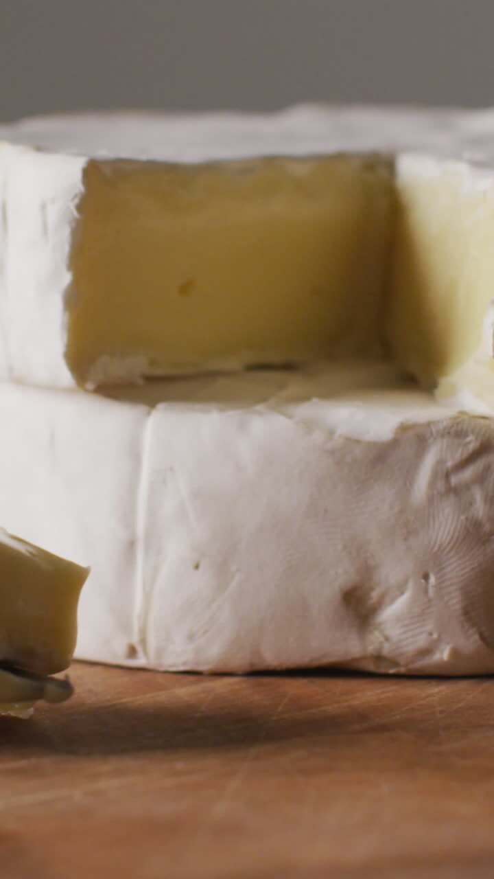 Video close up of soft cheeses and knife on wooden chopping board, with copy space