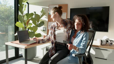 using laptop and holding credit card, lesbian couple shopping online at home
