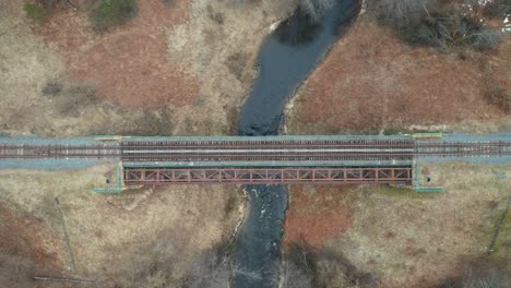 aerial: river flows below old railroad bridge in lithuania