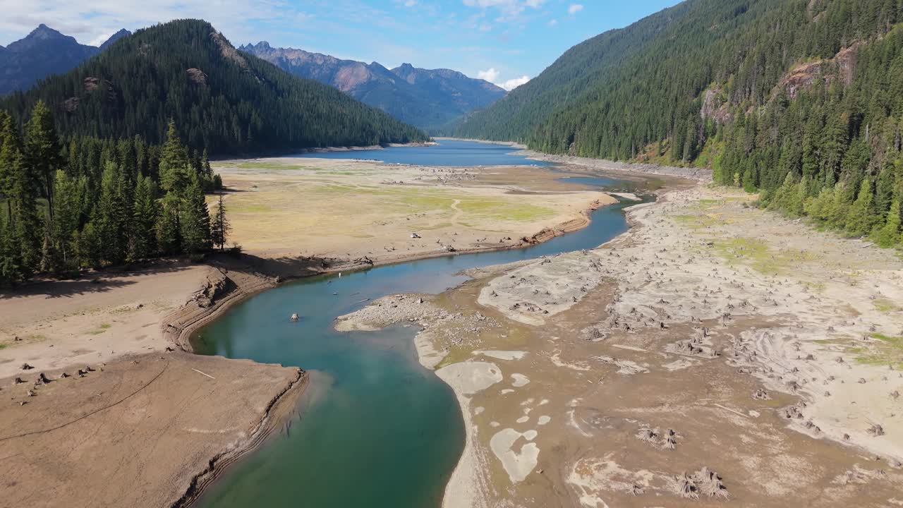 Drought-stricken lake surrounded by mountains and forest