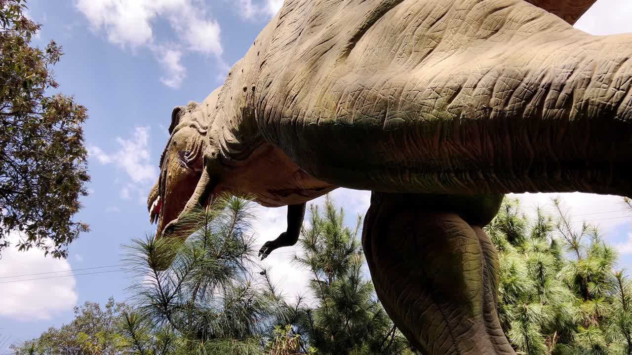 Bottom-up shot of a dinosaur moving and opening its mouth to roar in an open-air museum