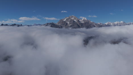 aerial view approaching a rocky mountain in middle of low hanging clouds in nepal