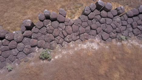 aerial dolly shot looks down onto basalt column tops along cliff face