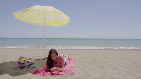 Mujer-En-Llamada-Telefónica-En-La-Playa-Bajo-El-Paraguas