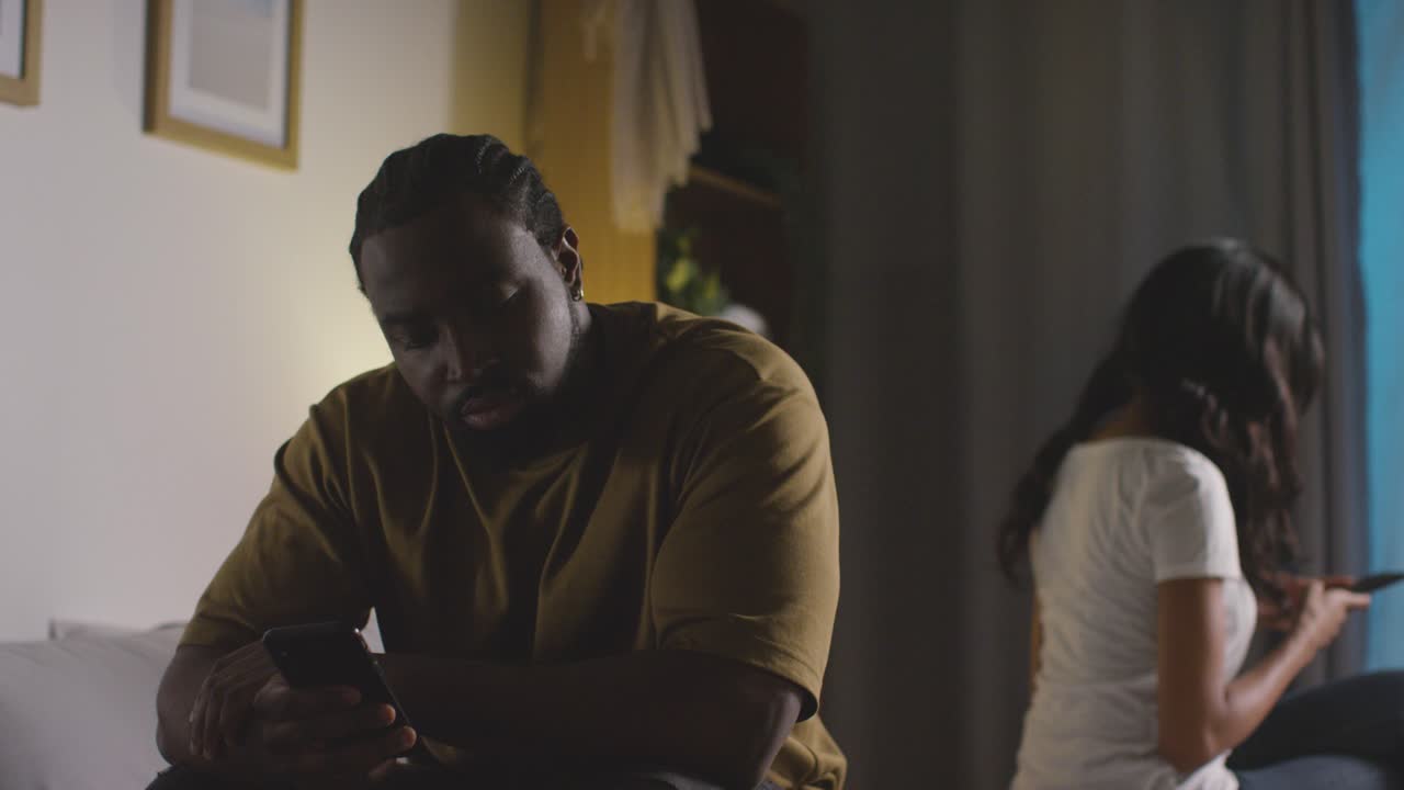 pareja con problemas de relación en casa por la noche ambos mirando teléfonos móviles en el dormitorio 8