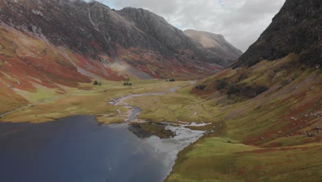 slowly flying above a highland valley and lake surrounded on either side by scottish mountains in the glencoe area of scotland