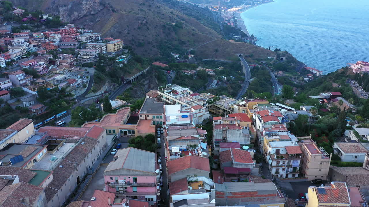 Flying over the medieval Sicilian city in the afternoon; Mediterranean sea in the background. Aerial landscape; Taormina, Italy.