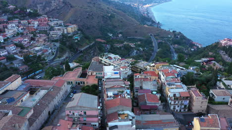 flying over the medieval sicilian city in the afternoon; mediterranean sea in the background. aerial landscape; taormina, italy.