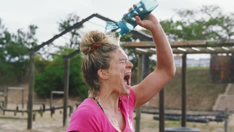 caucasian woman pouring water on her face at bootcamp