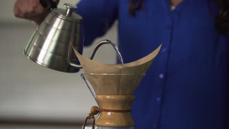 kettle pouring boiling water over coffee filter, steam rising, slow motion