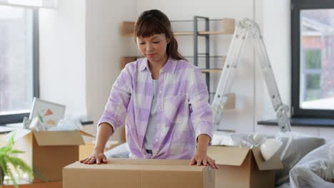 Women-with-Adhesive-Tape-Packing-Boxes-at-Home.moving,-people-and-real-estate-concept--women-with-adhesive-tape-packing-boxes-at-home