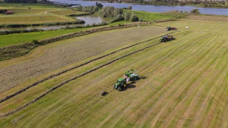 aerial view of working farmers producing hay bales with modern tractors