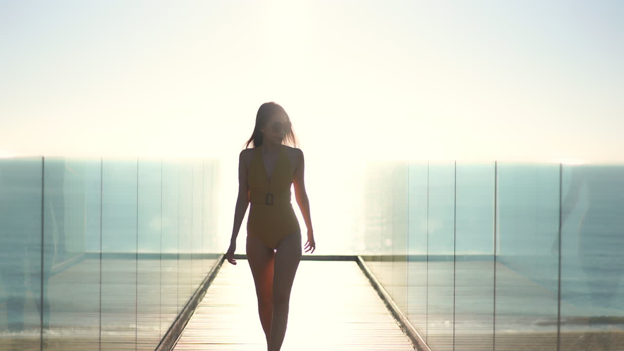 Donna misteriosa in costume da bagno che cammina in un corridoio luminoso con riflesso dello specchio sulle pareti, al rallentatore. Scena futuristica da sogno
