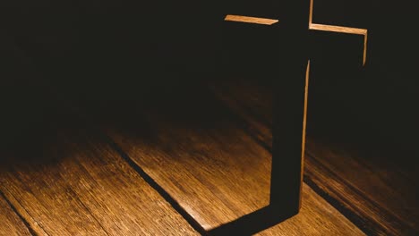 wooden christian cross casting shadow over wooden surface