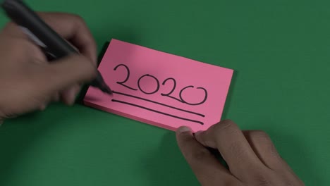 Male-Left-Hand-Writing-2020-On-Pink-Post-It-Note-And-Underlining-It