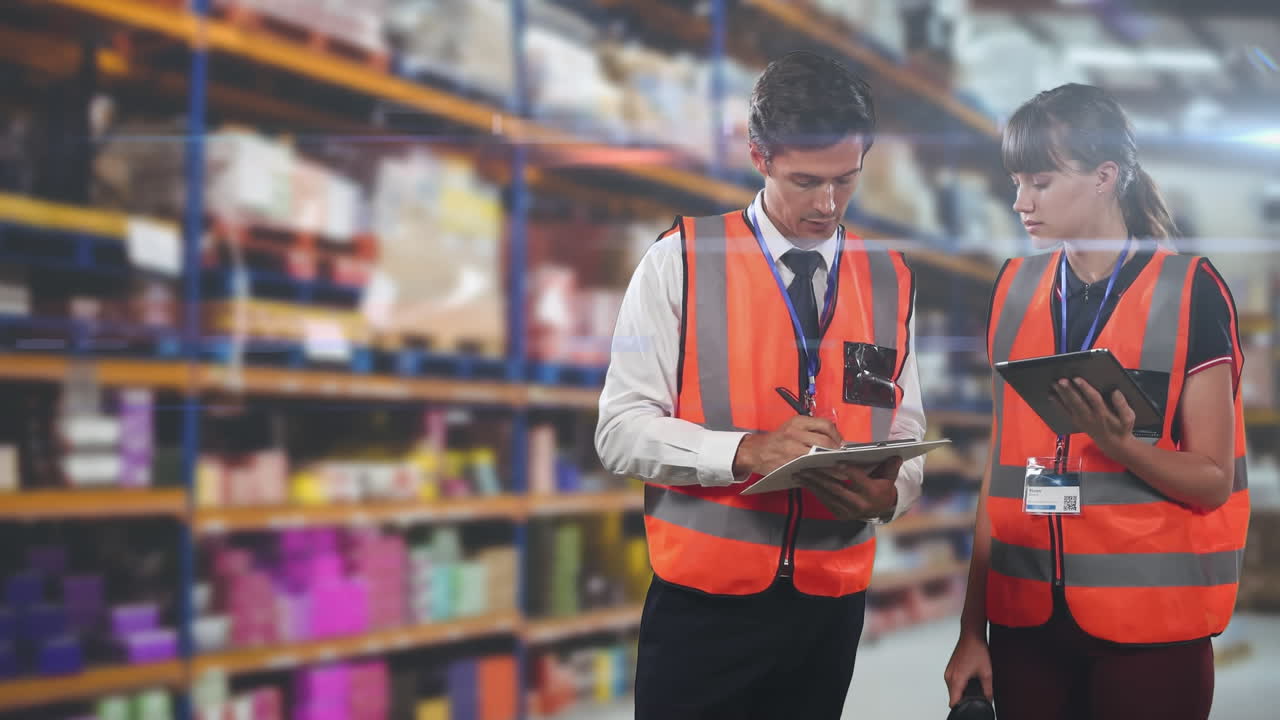 Trabajadores caucásicos (hombre y mujer) con chalecos naranjas de alta visibilidad, revisando notas en un área de almacén.