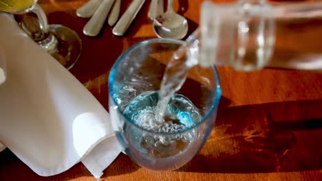 imágenes en cámara lenta de agua embotellada de vidrio que se vierte en un vaso en un juego de mesa